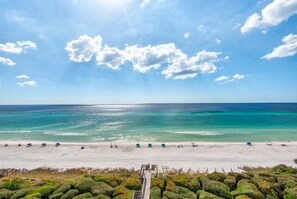 Une plage avec un ciel dégagé, une mer calme et un sentier qui mène au bord de l’eau.