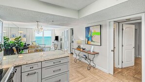 A spacious kitchen with a large island, a dining area with a view, and a living room with a balcony.