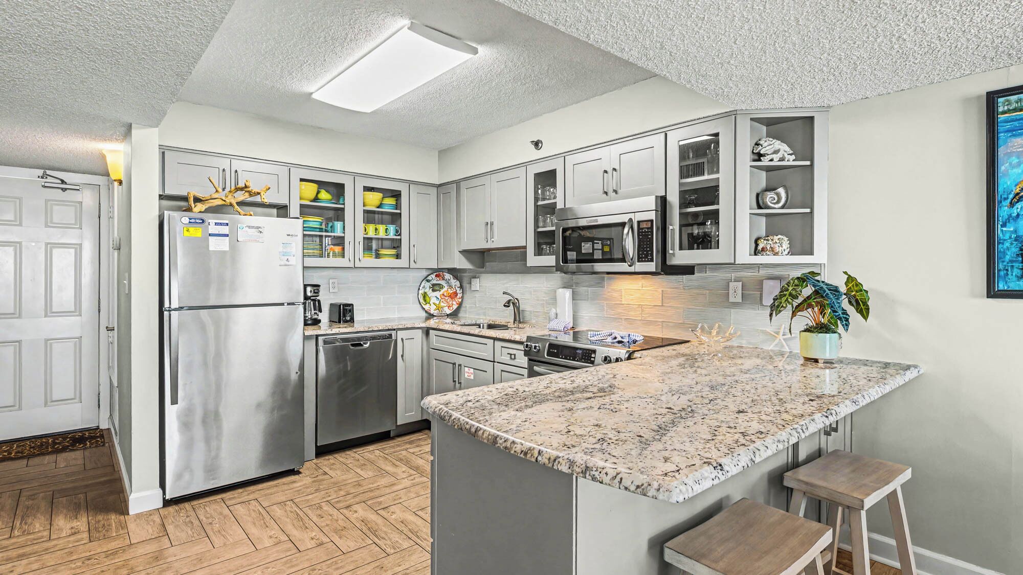A modern kitchen with stainless steel appliances, a granite countertop, and a herringbone-patterned backsplash.