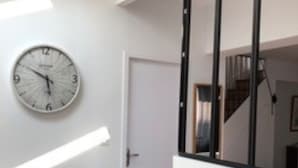A modern room with a black countertop, a white wall-mounted clock, and a door. - Beautiful renovated house on the waterfront (Treffiagat)
