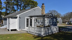 Ein Haus mit einer Veranda, einem Schornstein und einem umzäunten Garten.