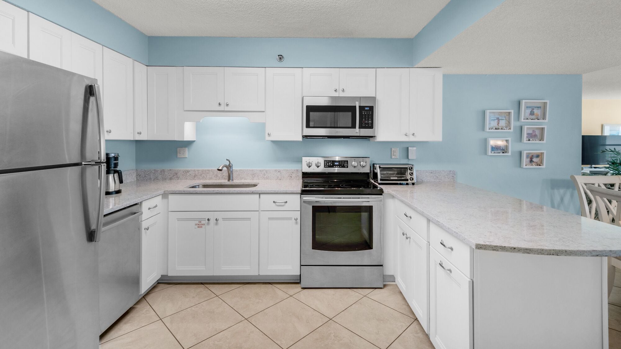 A modern kitchen with white cabinets, stainless steel appliances, a microwave, a stove, and a sink.