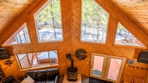 A cozy cabin with a wooden interior, large windows, a fireplace, and a leather couch.