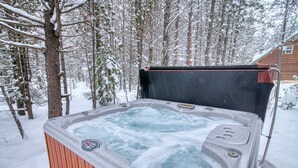 A hot tub in a snowy forest setting.