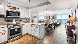 A modern kitchen with stainless steel appliances, a large island, and a dining area with a view.