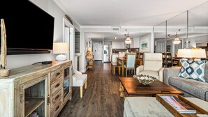 A spacious living area with a wooden coffee table, a sofa with patterned cushions, and a dining table with chairs.