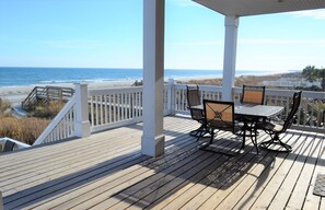 A wooden deck with a white railing overlooking a beach.