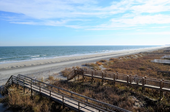 A beach with wooden boardwalks leading to the shore, sandy beach, and ocean.
