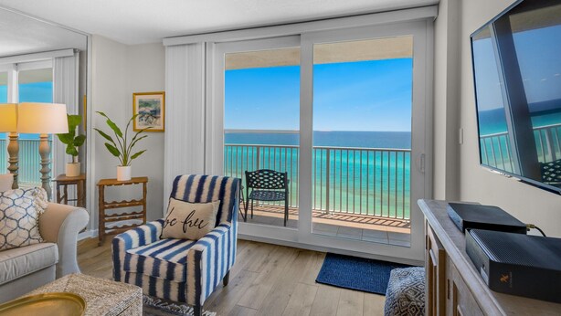 A room with a sofa, armchair, and a television. There is a balcony with a view of the ocean. - Gulf-Front w/ Private Beach Access + Free Beach Setup & Attraction Tickets! (Santa Rosa Beach)