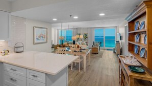 A modern kitchen with a large island, dining area with a view of the ocean, and a living room with a balcony overlooking the sea. - Gulf-Front w/ Private Beach Access + Free Beach Setup & Attraction Tickets! (Santa Rosa Beach)