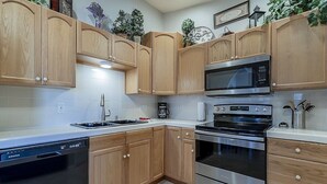 A kitchen with wooden cabinets, a stainless steel microwave, an oven, and a dishwasher. - Quiet Retreat w/ AC | Chelsea Park Casita (Mesa)