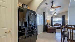 A compact kitchen with a black refrigerator, a dining area with a table and chairs, and a ceiling fan. - Quiet Retreat w/ AC | Chelsea Park Casita (Mesa)