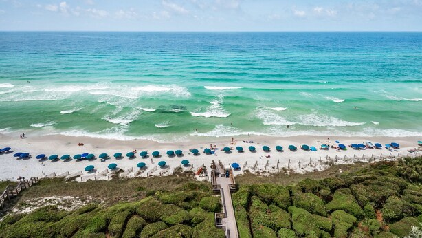 A beach with rows of umbrellas and a wooden walkway leading to the water. - Gulf Front w/ Private Beach, Free Seasonal Beach Chairs & Attraction Tickets! (Santa Rosa Beach)