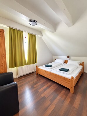 Quarto com cama de madeira, uma cadeira preta e radiador.