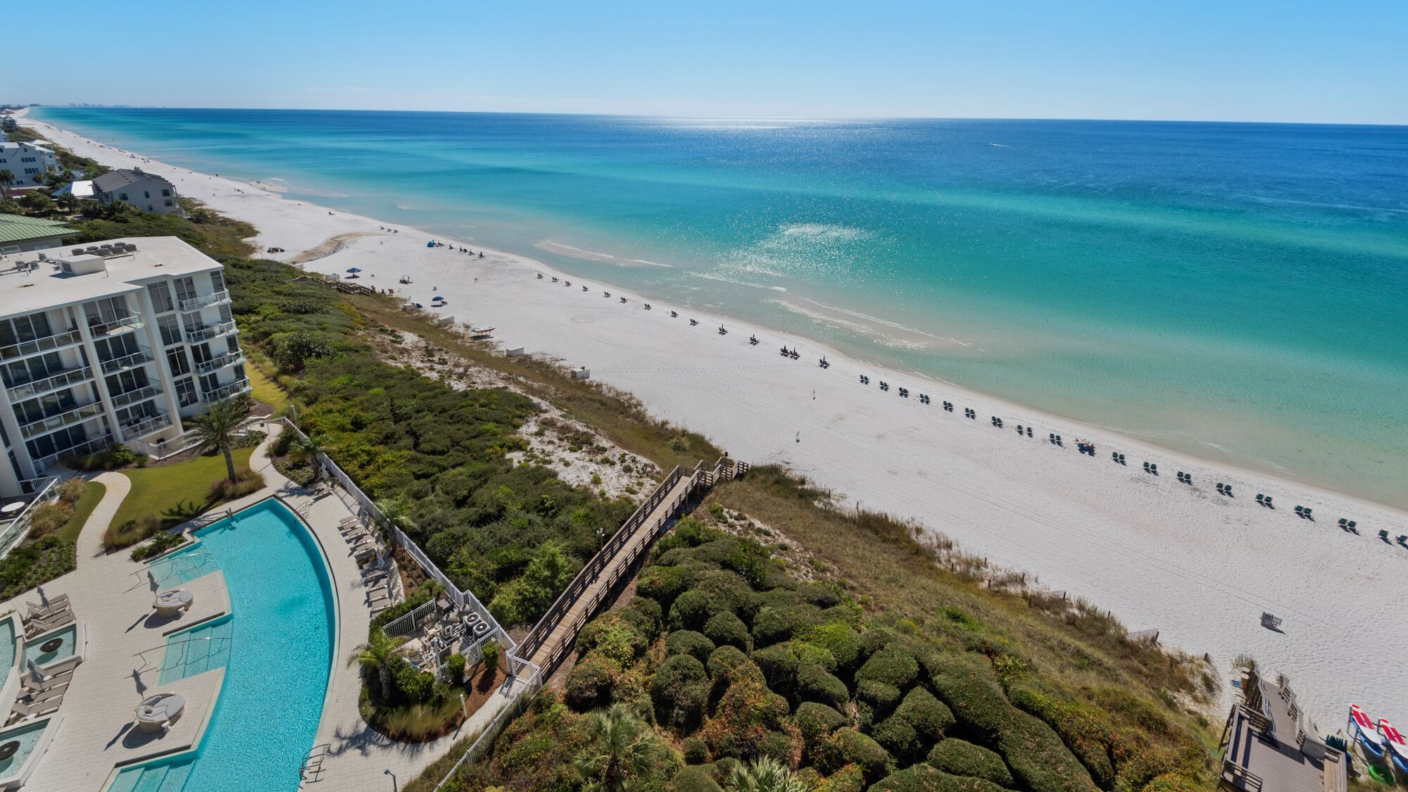 Ein Resort mit Strand, Pool und einer Brücke, die die Gebäude mit dem Strand verbindet.