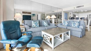Uma sala de estar moderna com uma poltrona de couro azul, um sofá listrado e uma mesa de centro de madeira.