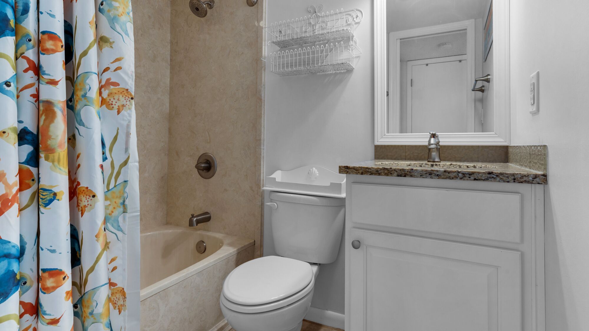 A bathroom with a bathtub, toilet, and a sink with a granite countertop.