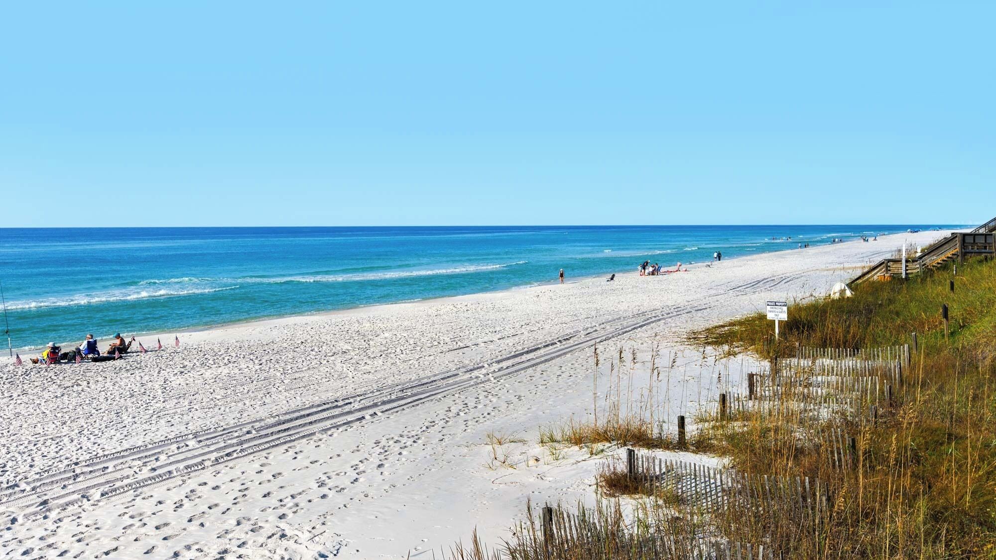 A beach with a wooden boardwalk, sandy beach, and ocean.