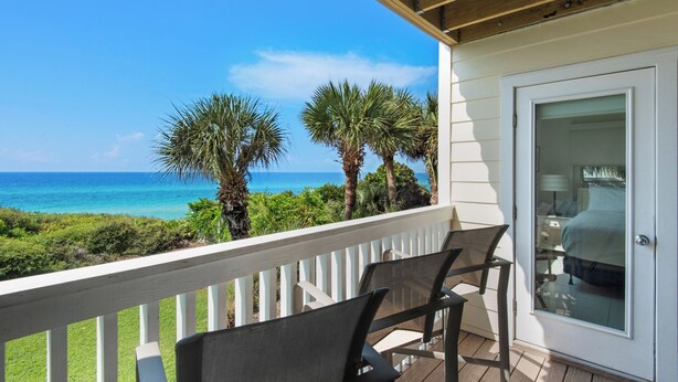 A balcony with two chairs, a door with a glass panel, and a view of the ocean and palm trees. - Dog Friendly Gulf-Front Condo in Seagrove Beach, Sleeps 6 + Free Tickets! (Santa Rosa Beach)