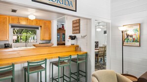 A kitchen with wooden cabinets, a wooden bar counter, and green bar stools. - Beautiful Seaside Cottage, Sports Club, Sleeps 6 + Free Attraction Tickets! (Seaside)