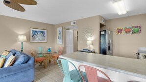 A compact kitchen with a dining area, featuring a refrigerator, a small island, and a dining table with chairs.