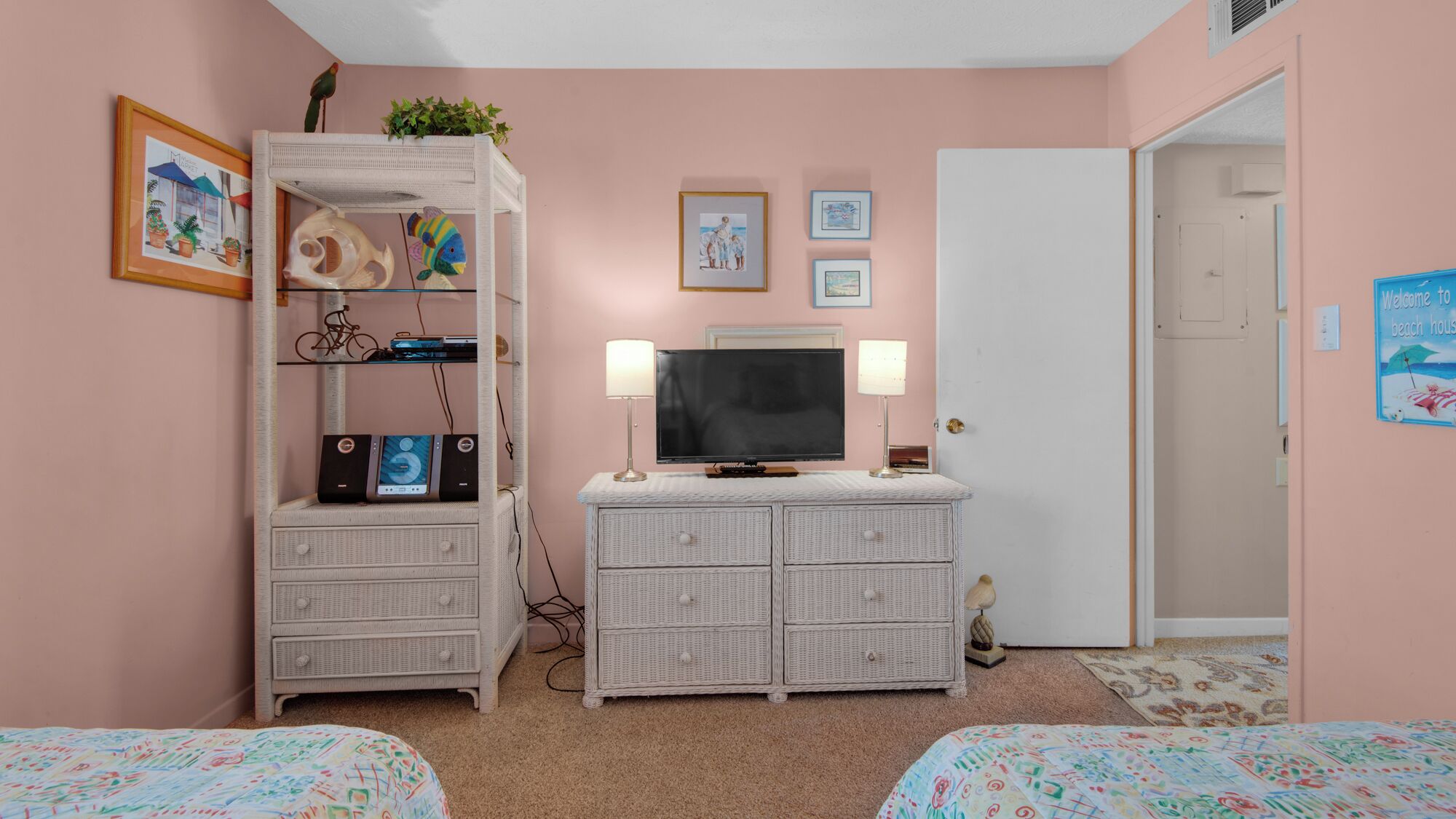 A bedroom with two beds, a white dresser, a TV, and wall art.