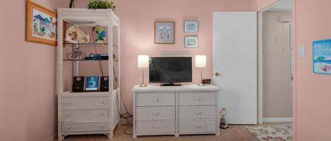 A bedroom with two beds, a white dresser, a TV, and wall art.