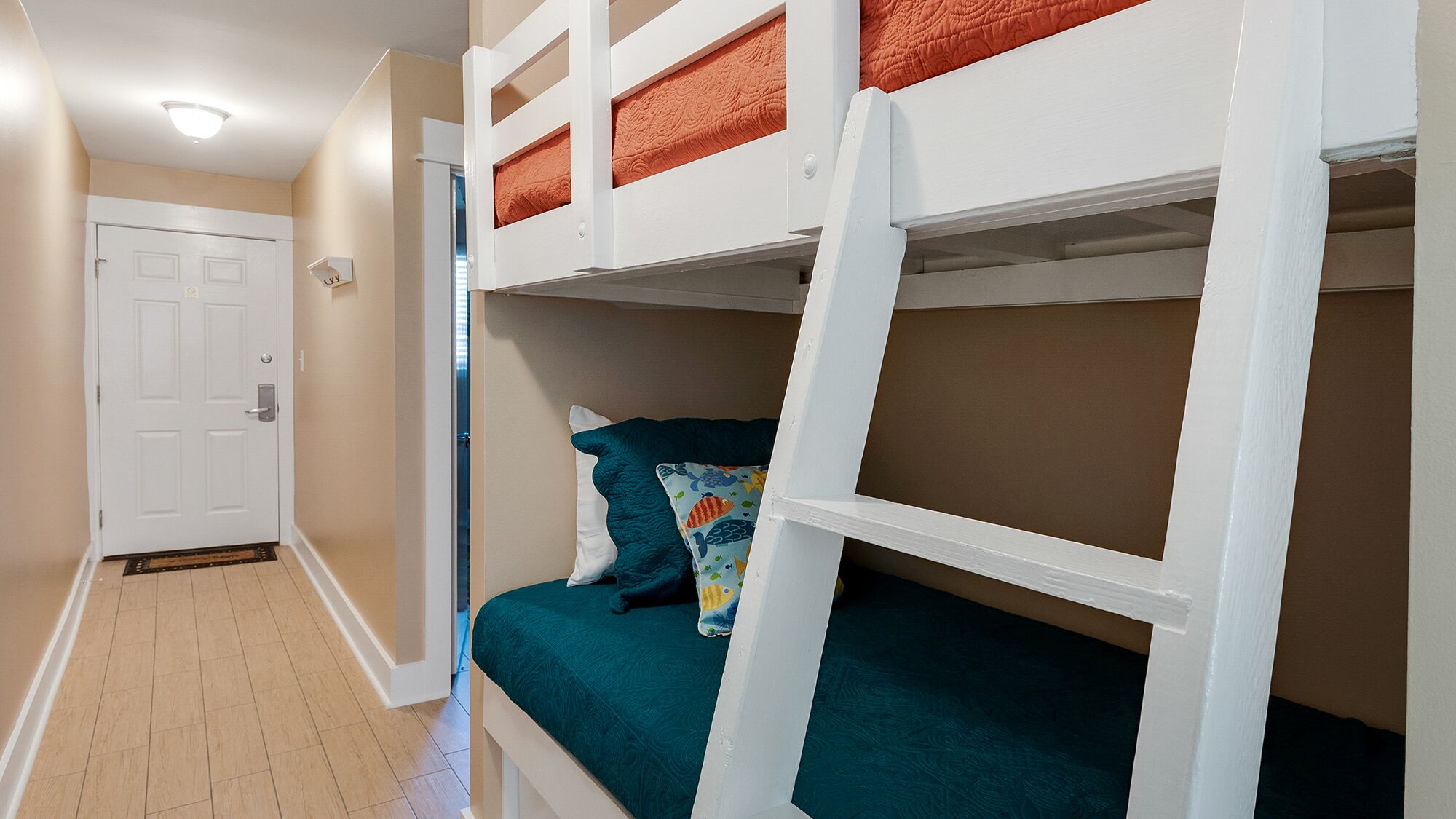 A bunk bed room with a door, a light switch, and a patterned pillow.