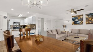 A modern living room with a wooden dining table, beige sofas, and a ceiling fan. - Gulf Side in Seagrove Beach, Awesome Location + Free Attraction Tickets! (Santa Rosa Beach)