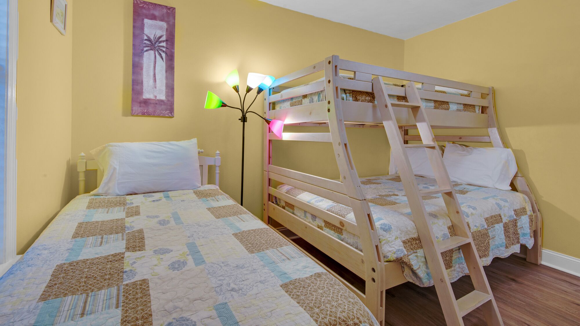 Una stanza con due letti a castello, un comodino, una lampada e una decorazione a parete.