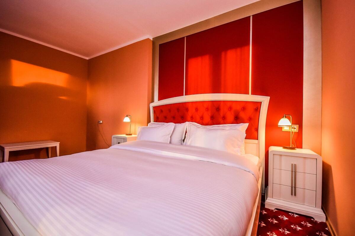 Habitación de hotel con una cama grande, dos mesitas de noche y un armario.