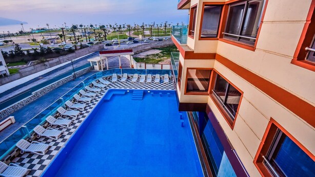 Uma piscina no terraço com espreguiçadeiras, vista da região circundante e um edifício com varandas.