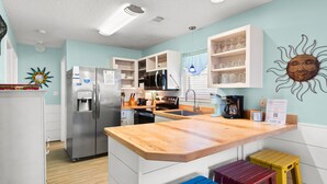 Una cocina moderna con refrigerador, microondas y estufa integrados, encimeras de madera y una decoración de pared con motivos solares.