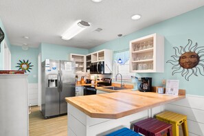 Cocina moderna con refrigerador, microondas y estufa incorporados. Tiene una encimera de madera y un lavamanos.
