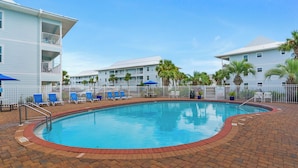 A swimming pool surrounded by a brick patio, with lounge chairs and umbrellas, and a multi-story building with balconies in the background. - Steps from the Gulf ~ 2 Community Pools ~ Tennis + Free Attraction Tickets! (Santa Rosa Beach)