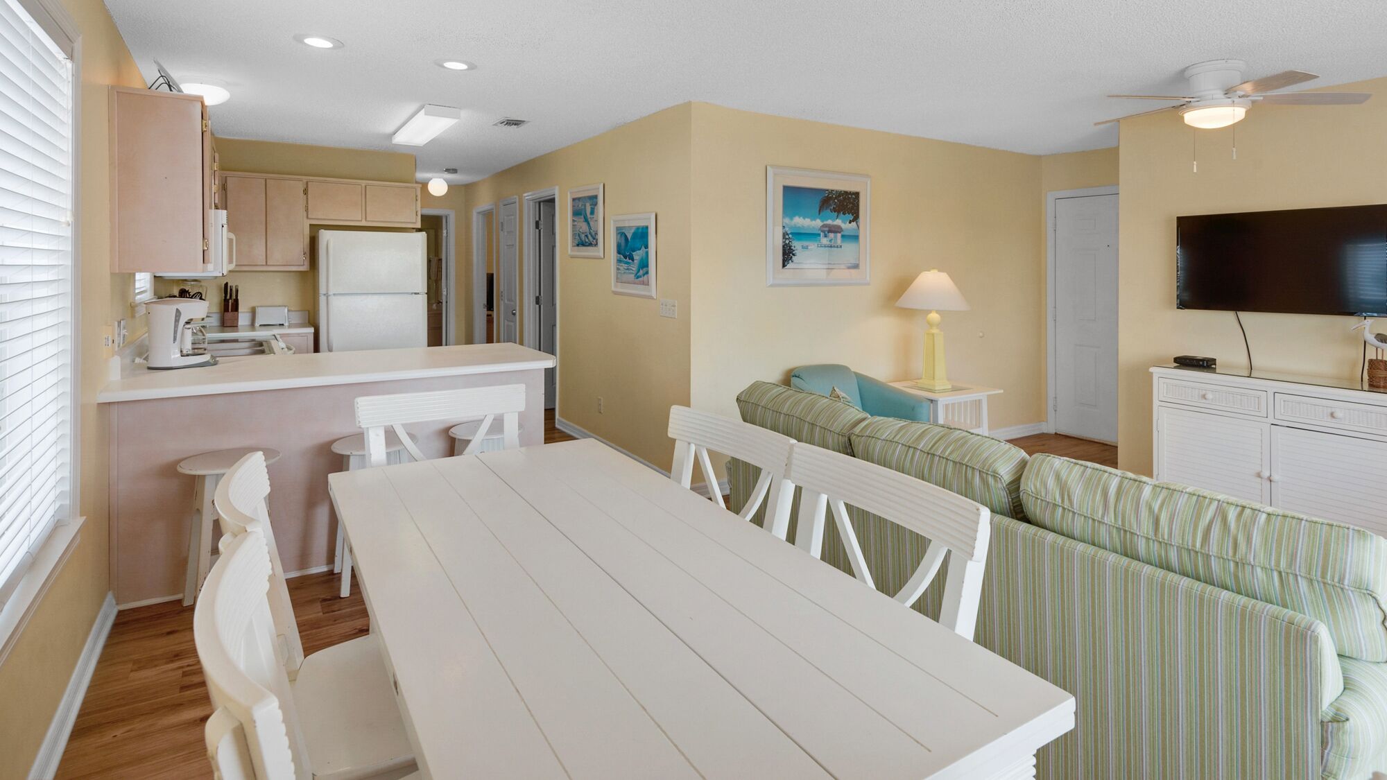 A compact living space with a kitchenette, a dining area, a sofa, and a television.