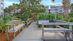 A wooden boardwalk leading to a building with a 'NOTICE: NO SQUARE CANOPIES PERMITTED ON THE BEACH' sign. - Ground Floor, 2 Pools, Tennis, Beautiful Community + Free Attraction Tickets! (Santa Rosa Beach)