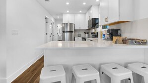 A modern kitchen with white cabinets, stainless steel appliances, and a marble countertop. - Modern Updates, Family Friendly, Near to Beach,2 Pools, Tennis +Free Tickets! (Santa Rosa Beach)