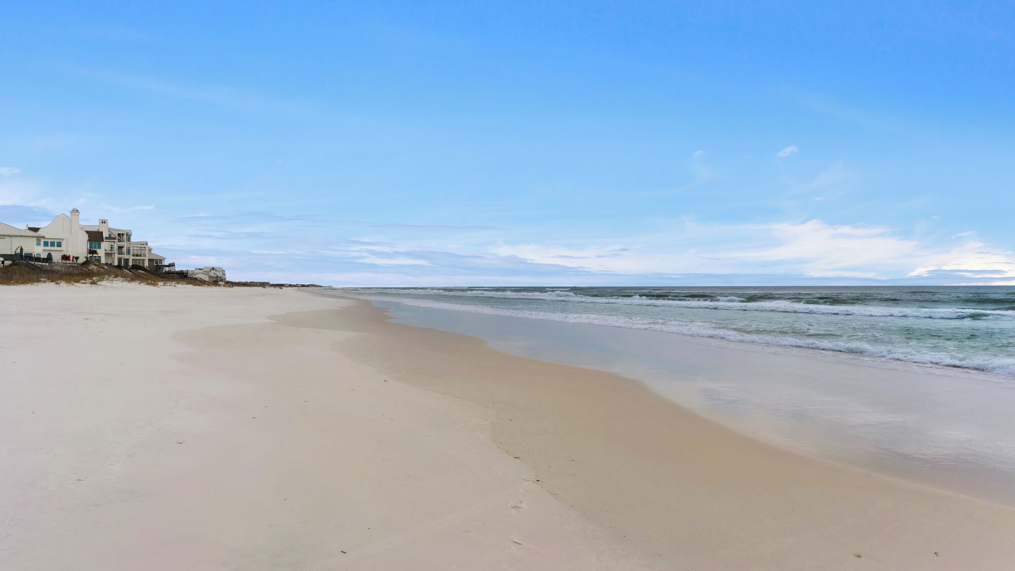 A beach with a large house on the left.