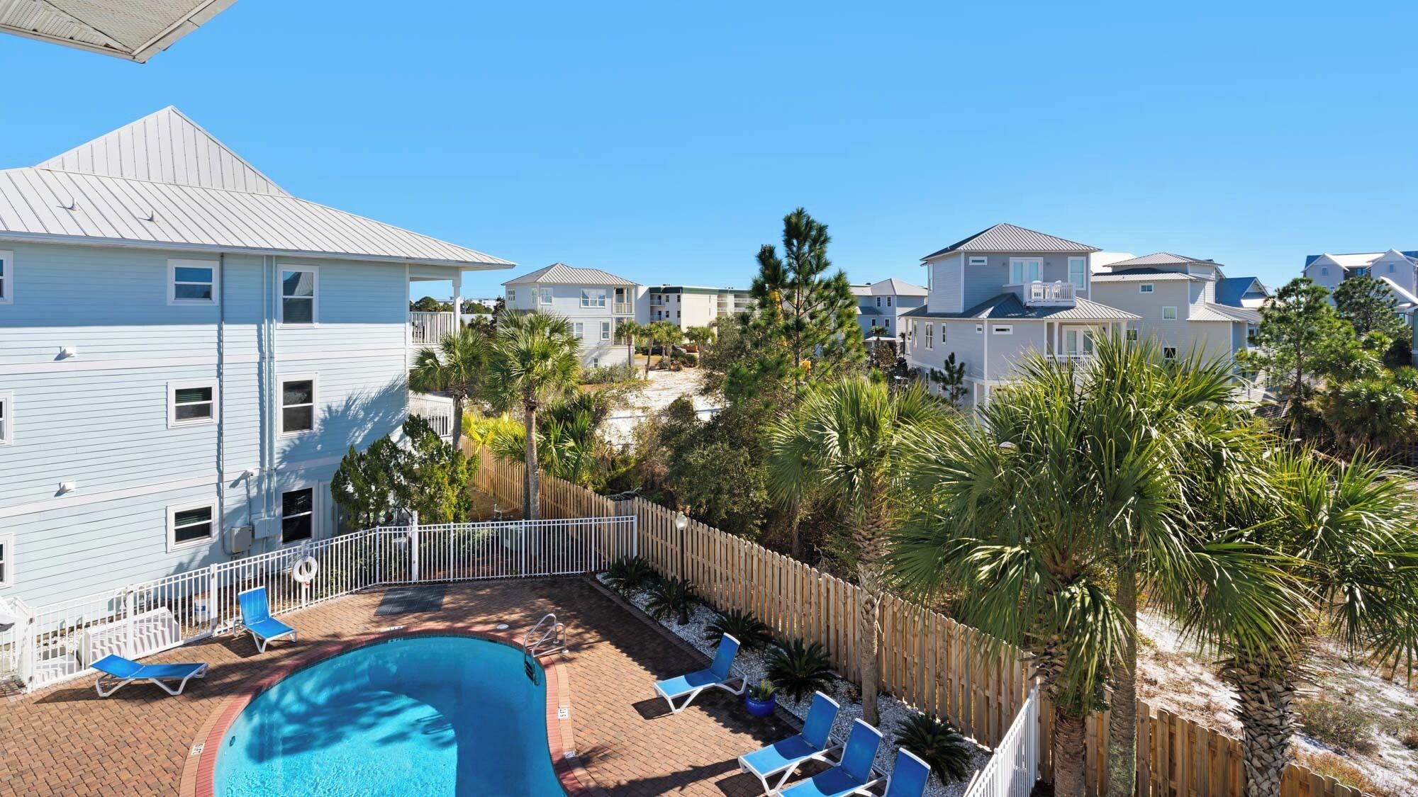 Uma área residencial com piscina, espreguiçadeiras e cerca de madeira.