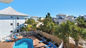 A residential area with a swimming pool, lounge chairs, and a wooden fence. - Modern Updates, Family Friendly, Near to Beach,2 Pools, Tennis +Free Tickets! (Santa Rosa Beach)