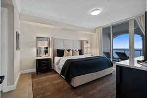 A modern hotel room with a large bed, a desk, and a view of the ocean. - Beach Club 1004 - 𝑨𝒎𝒃𝒆𝒓 𝑺𝒖𝒏𝒓𝒊𝒔𝒆 (Pensacola Beach)