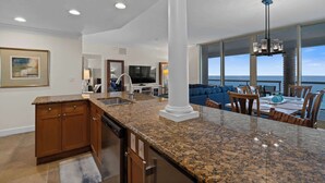 Una cocina moderna con encimeras de granito, una isla central y un comedor con vista al océano.