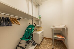 A small, well-organized storage area with shelves, a stroller, and a baby changing station. - Ca 'dell'Affresco close to Saint-Mark's square and Rialto Bridge! (Venezia)
