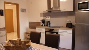 A compact kitchen with a microwave, stove, and a coffee maker. There is a sign that says "KITCHEN" on the wall. - New apartment in the middle of vineyards (Coswig)