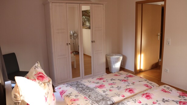A bedroom with a bed, a wardrobe, and a mirror. - New apartment in the middle of vineyards (Coswig)