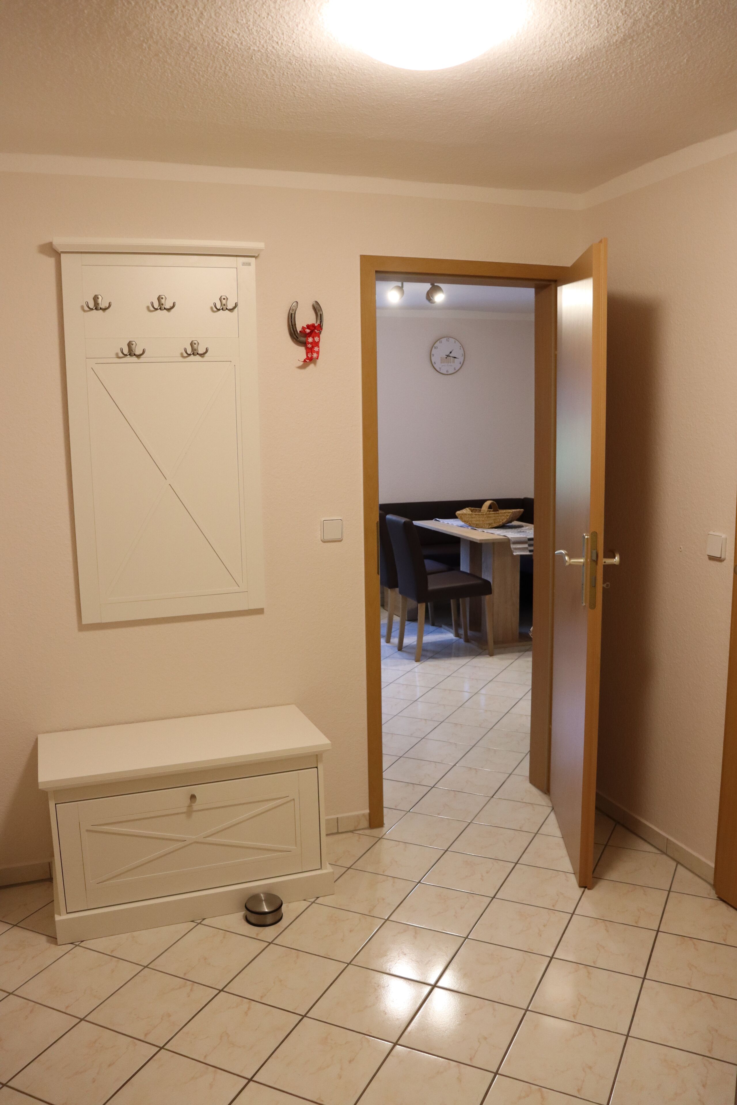 Un couloir avec un banc, un porte-manteau et une porte donnant sur un espace repas.