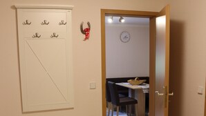 A hallway with a white bench, a door leading to a dining area, and a wall-mounted clock. - New apartment in the middle of vineyards (Coswig)