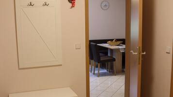 Un couloir avec un banc, un porte-manteau et une porte donnant sur un espace repas.