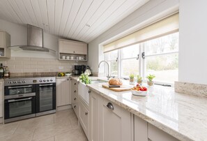 A modern kitchen with a built-in oven, a stainless steel range hood, and a large window providing natural light.